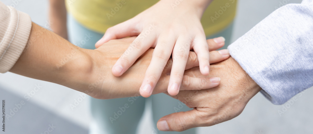 Fototapeta premium Header crop of Lovely Asian three generation family with grandfather and mother putting hand together, concept of strong family love and family togetherness