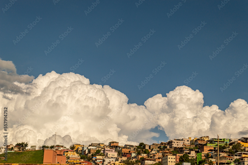 Beautiful landscape with blue sky many clouds and houses at the top of the hill.