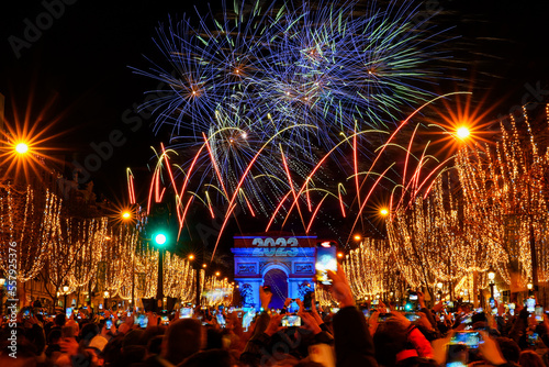 Paris, France - January 1st, 2023 : New Year's fireworks over the Arc de Triomphe (triumphal arch) on the Champs Elysées in Paris to celebrate the passing to 2023 on front of a large crowd #557925376