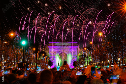 Paris, France - January 1st, 2023 : New Year's fireworks over the Arc de Triomphe (triumphal arch) on the Champs Elysées in Paris to celebrate the passing to 2023 on front of a large crowd photo