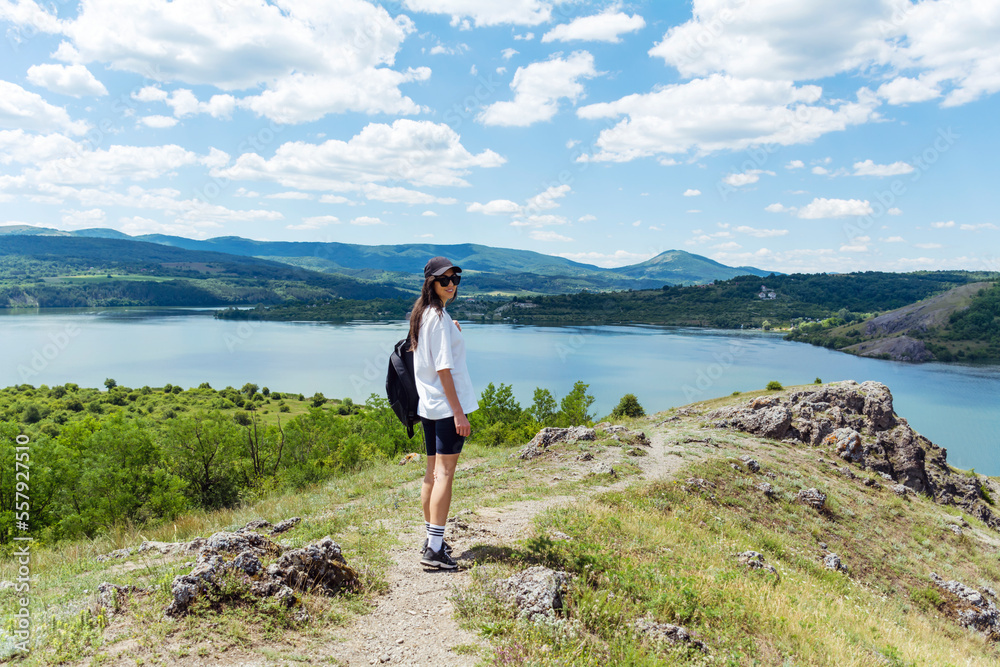 Young traveler woman walking  in the mountain above blue lake .Traveling in the summer nature in Bulgaria	. Pchelina Lake 