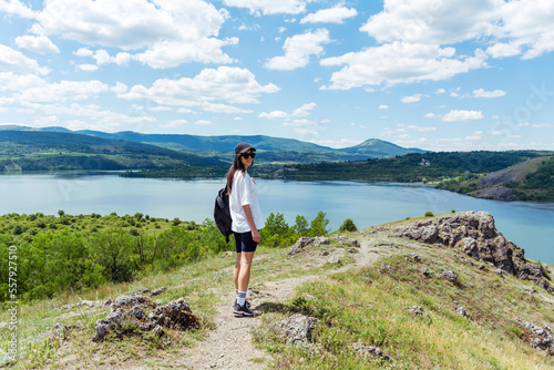 Young traveler woman walking  in the mountain above blue lake .Traveling in the summer nature in Bulgaria	. Pchelina Lake  photo