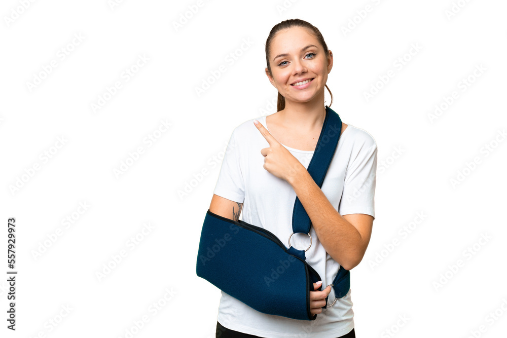 Young blonde woman with broken arm and wearing a sling over isolated chroma key background pointing to the side to present a product Young blonde woman with broken arm and wearing a sling over isolated chroma key background pointing to the side to present a product