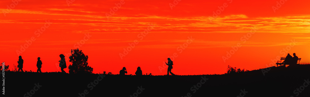 Silhouette of young people in sunset with beautiful orange sky in background, youth lifestyle and fun concept