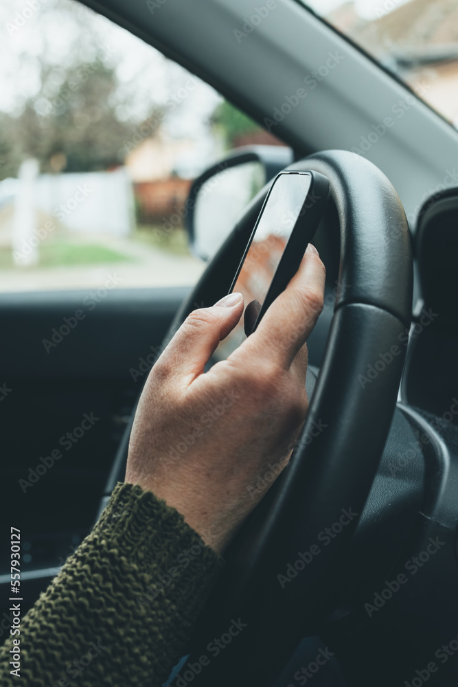 Closeup shot of female hand typing message on smartphone device, casual woman driver wearing green knitted sweater using mobile phone in vehicle interior Closeup shot of female hand typing message on smartphone device, casual woman driver wearing green knitted sweater using mobile phone in vehicle interior