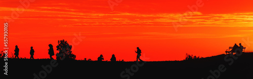 Silhouette of young people in sunset with beautiful orange sky in background, youth lifestyle and fun concept