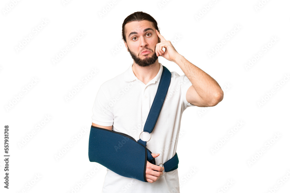 Young handsome man with broken arm and wearing a sling over isolated chroma key background thinking an idea Young handsome man with broken arm and wearing a sling over isolated chroma key background thinking an idea