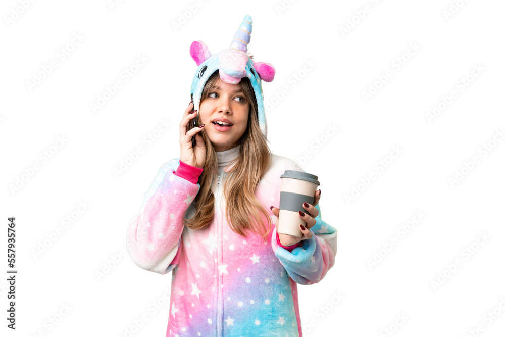 Young girl with unicorn pajamas over isolated chroma key background holding coffee to take away and a mobile Young girl with unicorn pajamas over isolated chroma key background holding coffee to take away and a mobile