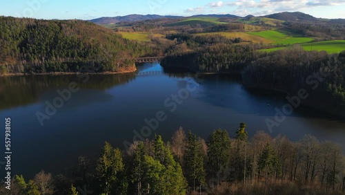 Aerial view of steel underspanned suspension railway bridge over Bobr River in Pilchowice, Wonderfull lake with islands and green forests in mountains on a sunny early spring day in Pilchowice, Poland photo