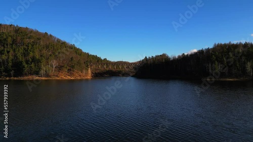 Aerial view of steel underspanned suspension railway bridge over Bobr River in Pilchowice, Wonderfull lake with islands and green forests in mountains on a sunny early spring day in Pilchowice, Poland photo