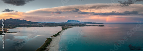 San Teodoro sand beach with lagoon, mountain of island Tavolara and coastline in Sadinia Italy from above during sunset, clouds and rainbow in sky