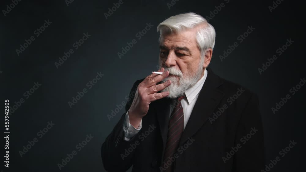 Close-up shot of old professor smoking a cigarette. Portrait of a thoughtful, concerned, adult man in his 70s living an unhealthy lifestyle. High quality 4k footage Close-up shot of old professor smoking a cigarette. Portrait of a thoughtful, concerned, adult man in his 70s living an unhealthy lifestyle. High quality 4k footage