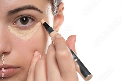 Woman  applying concealer on flawless fresh skin, doing make up. Girl  put corrector under eye area. photo