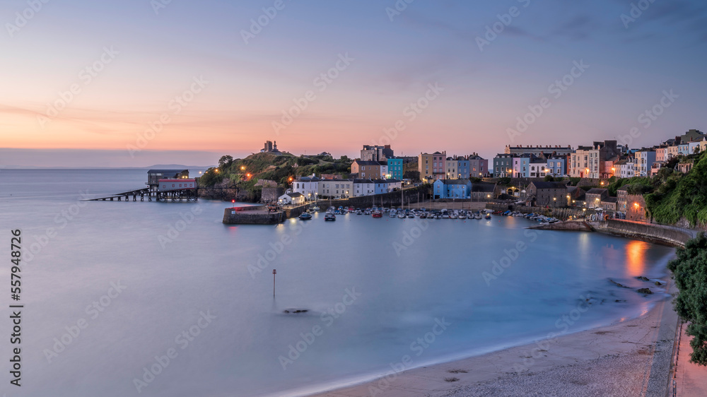 Obraz premium Sunrise over Tenby's harbour on a calm summer's morning. Tenby is a holiday destination on the south coast of Wales, UK