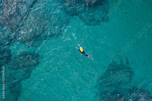 Aerial top view from drone of a swimmer in open water with wetsuit and buoy