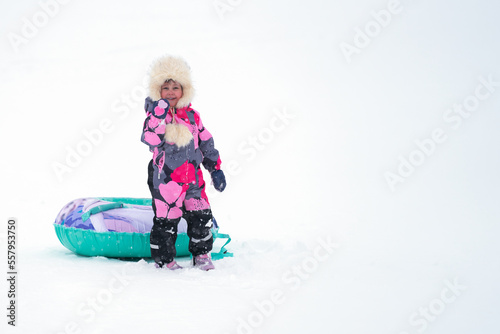 Downhill skiing. A happy child with a frosty blush on his face with an inflatable sled on a background of snow. Copy space.