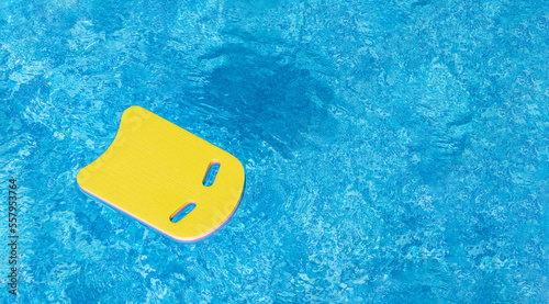 Safe pool training aid float foam board tool. Pink Swimming kickboard on blue water surface of swim pool. Mockup, Panoramic banner, copy space for text or design. Water sport, active lifestyle