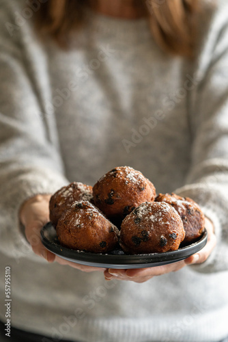 Close-up of a plate of oliebollen (Dutch doughnuts) with icing sugar held by a woman