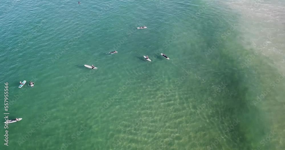 Aerial low angular perspective gliding above surfers floating on rippled Pacific waves in vibrant shades of blue and green Aerial low angular perspective gliding above surfers floating on rippled Pacific waves in vibrant shades of blue and green
