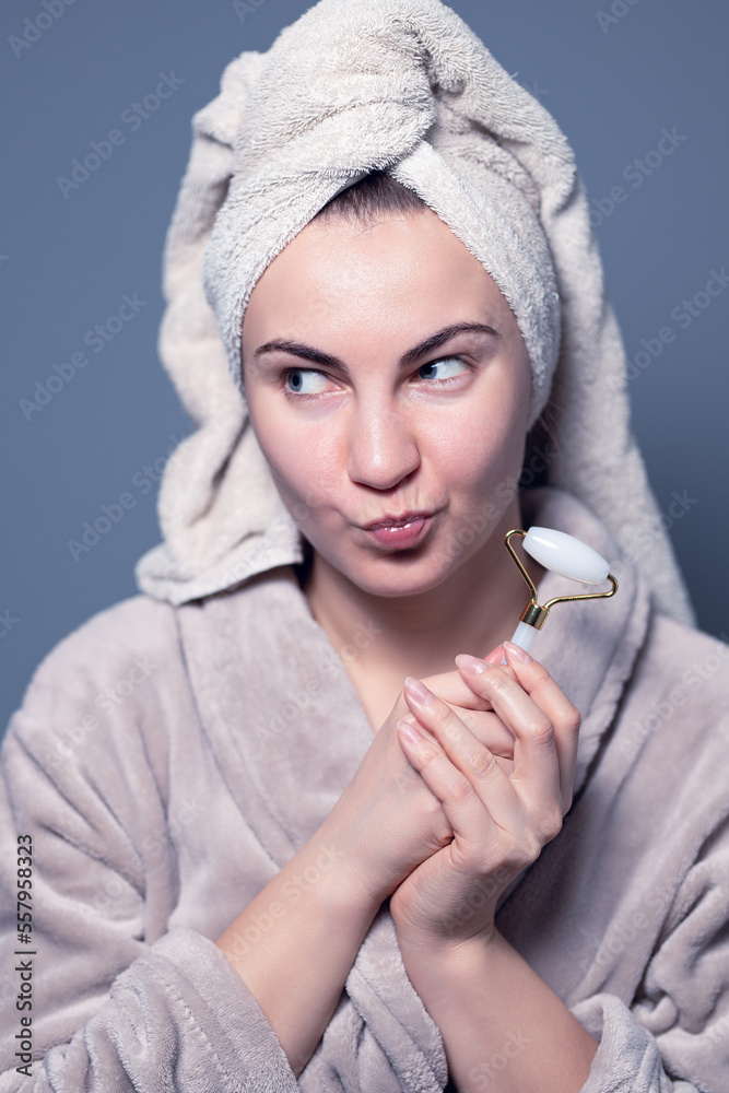 Obraz premium Women's beauty and spa. Beautiful woman using guasha jade stone roller massaging her face for a radiant complexion and healthy skin