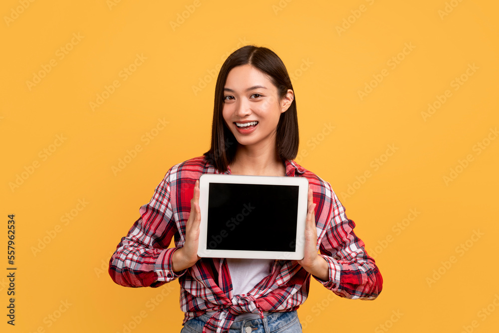 Asian lady showing digital tablet blank screen, advertising app or website, standing over yellow background, mockup Asian lady showing digital tablet blank screen, advertising app or website, standing over yellow background, mockup