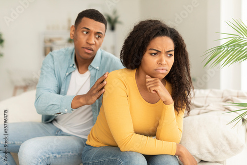 Sad husband calms offended upset millennial african american wife, ignore guy after quarrel in living room