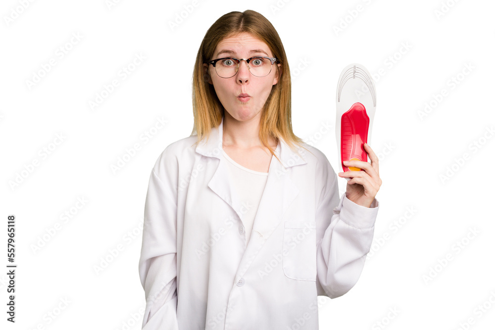 Young caucasian chiropodist woman holding an insoles for shoes isolated shrugs shoulders and open eyes confused. Young caucasian chiropodist woman holding an insoles for shoes isolated shrugs shoulders and open eyes confused.