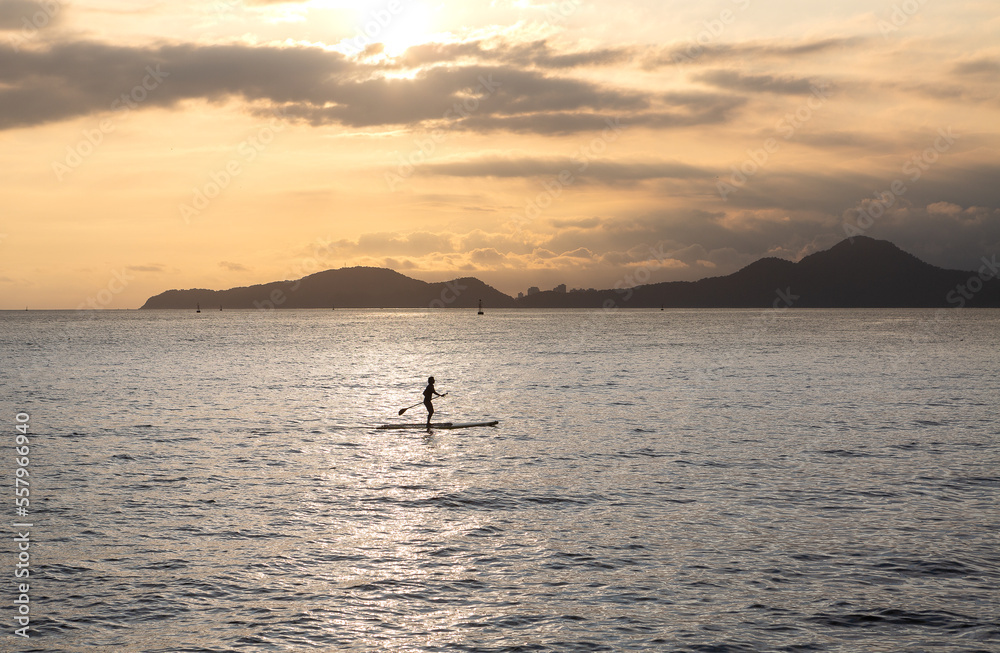 Girl practicing stand up paddle during the late afternoon in Santos bay Girl practicing stand up paddle during the late afternoon in Santos bay