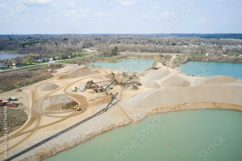 Large piles and mounds of sand at a sand pit. Large shovels and excavators load trucks.