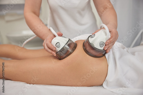 ultrasonic action  receiving massage  Slimming vacuum. Anti-cellulite roller vacuum massage takes place in medicine salon. Slim problem areas  special body care professional equipment  perform lpg