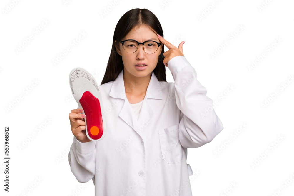 Young asian chiropodist holding a insoles for shoes isolated showing a disappointment gesture with forefinger. Young asian chiropodist holding a insoles for shoes isolated showing a disappointment gesture with forefinger.