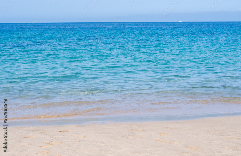 Stunning view of exotic colors on Lanzarote, Canary Islands, Spain, Europe. Turquoise color of the sea and crystalline sea. Sailboat on the horizon.