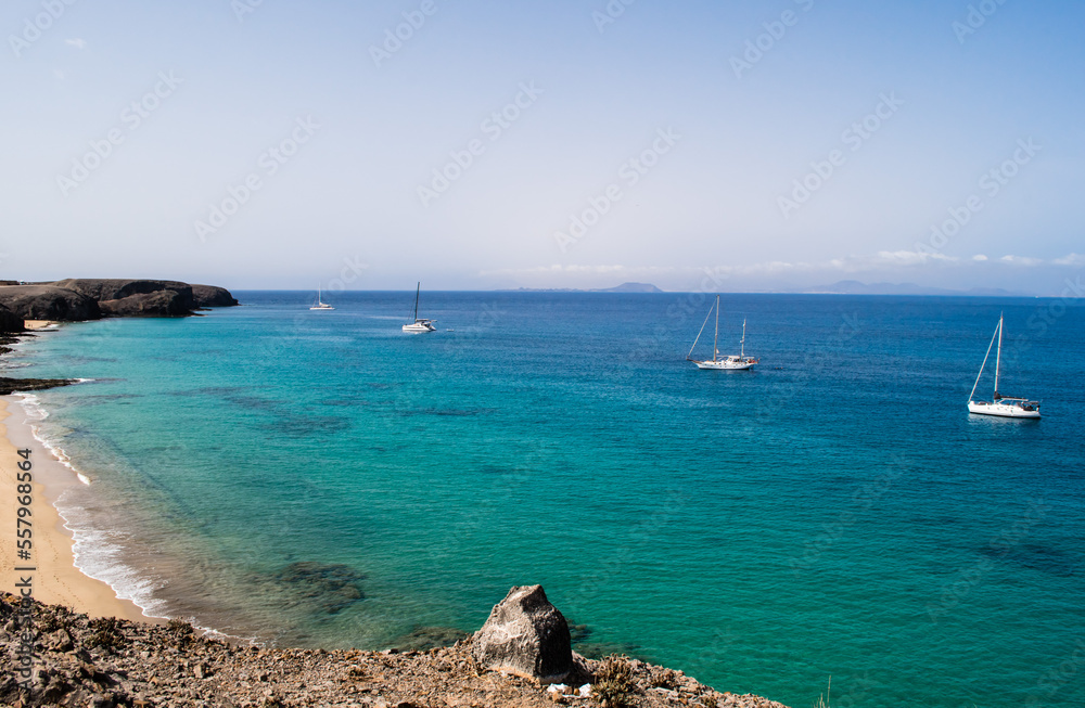 Stunning view of exotic colors on Lanzarote, Canary Islands, Spain, Europe. Turquoise color of the sea and crystalline sea. Sailboat on the horizon.