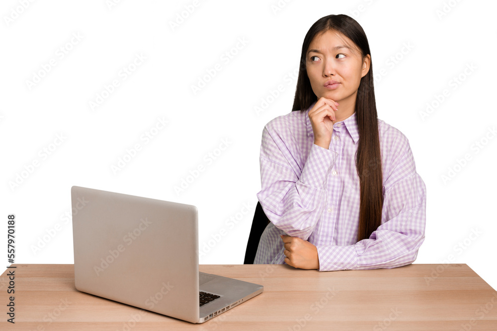 Young student asian woman in a workplace with a laptop isolated looking sideways with doubtful and skeptical expression. Young student asian woman in a workplace with a laptop isolated looking sideways with doubtful and skeptical expression.
