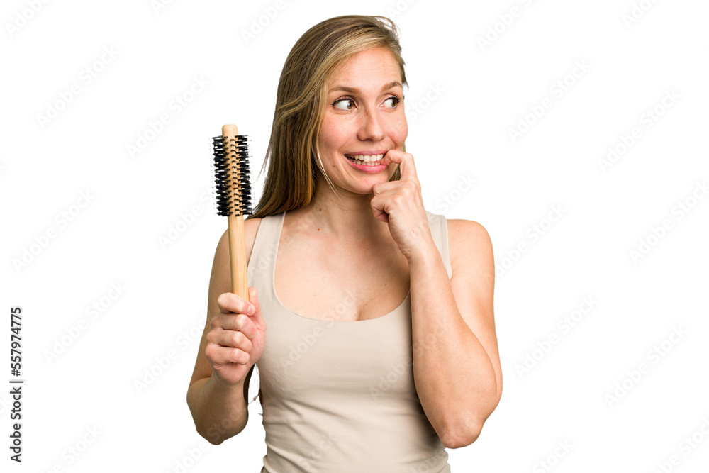 Young caucasian woman using an hair comb isolated relaxed thinking about something looking at a copy space. Young caucasian woman using an hair comb isolated relaxed thinking about something looking at a copy space.