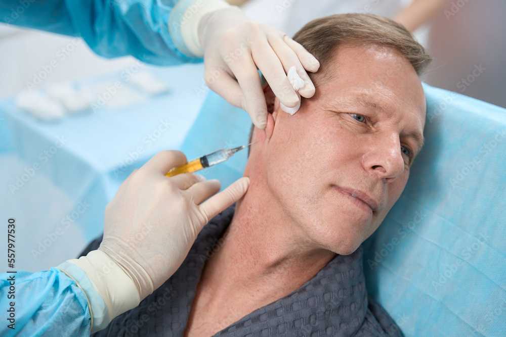 Adult man looking pleased during medical injection Adult man looking pleased during medical injection