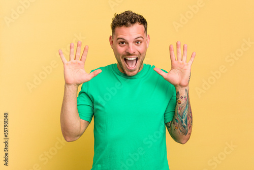 Young caucasian handsome man isolated on yellow background receiving a pleasant surprise, excited and raising hands.