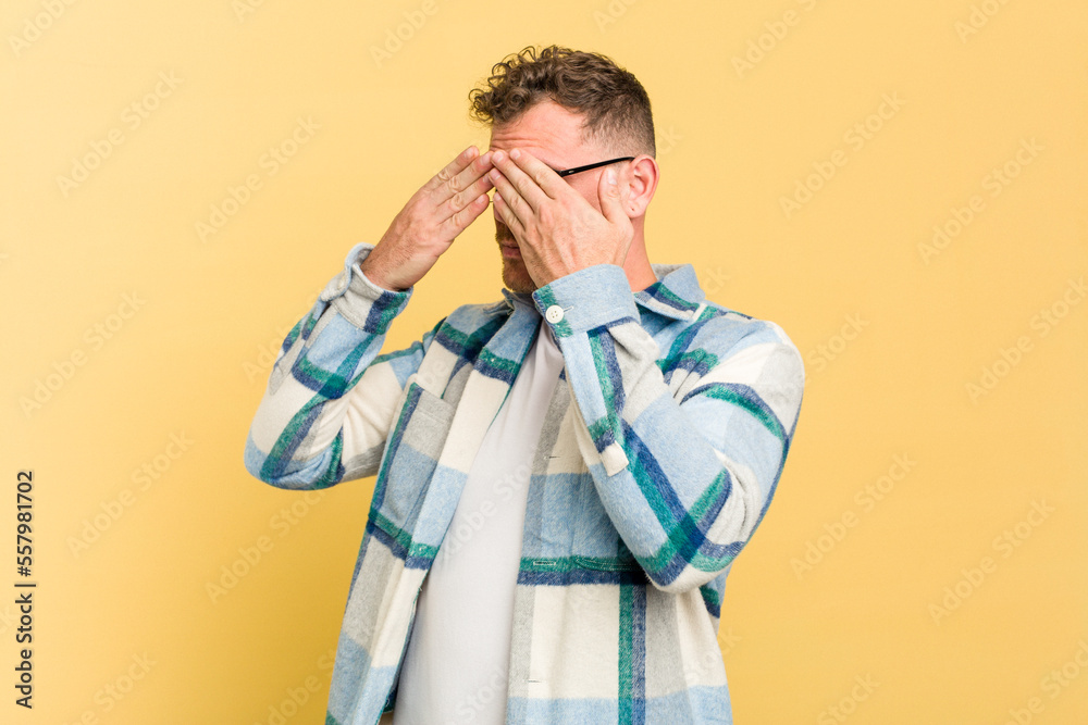 Young caucasian handsome man isolated on yellow background afraid covering eyes with hands. Young caucasian handsome man isolated on yellow background afraid covering eyes with hands.