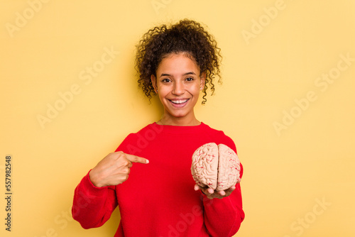 Young brazilian woman holding a brain model isolated person pointing by hand to a shirt copy space, proud and confident