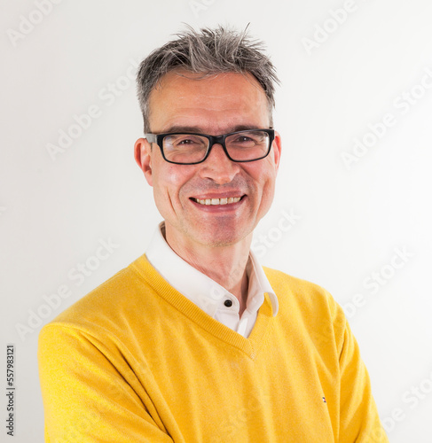 portrait of a man with glasses in business shirt and yeloow knitted pullover photo