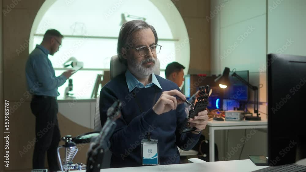Portrait of serious old smart man working in futuristic office building robotic prosthesis hand using screwdriver. Happy professional mature scientist looking at camera smiling. Portrait of serious old smart man working in futuristic office building robotic prosthesis hand using screwdriver. Happy professional mature scientist looking at camera smiling.