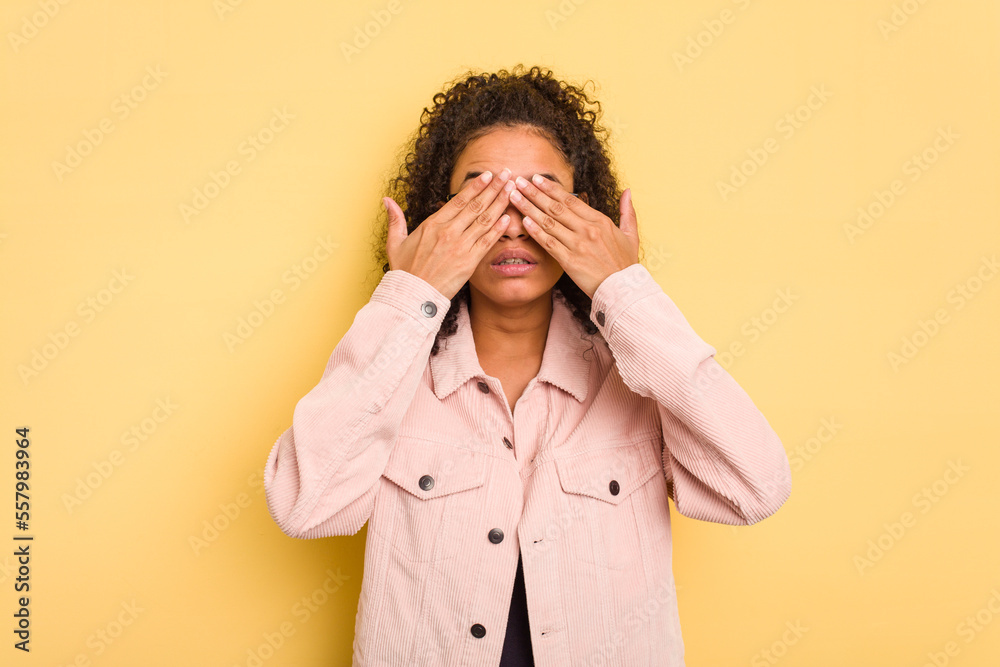 Young Brazilian curly hair cute woman isolated on yellow background afraid covering eyes with hands. Young Brazilian curly hair cute woman isolated on yellow background afraid covering eyes with hands.