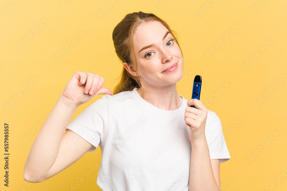Young cute woman holding a vaper isolated on yellow background feels proud and self confident, example to follow. Young cute woman holding a vaper isolated on yellow background feels proud and self confident, example to follow.
