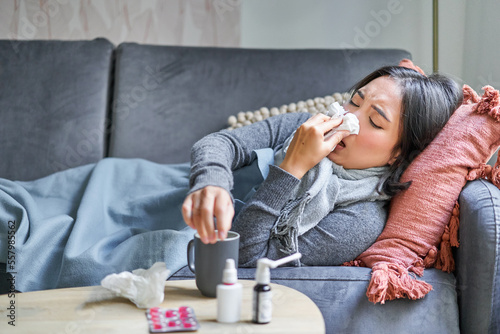 Fototapeta Sick woman lying on sofa at home, catching cold