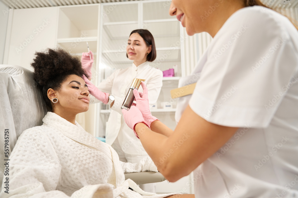 Two doctors and woman in beauty salon during procedures Two doctors and woman in beauty salon during procedures