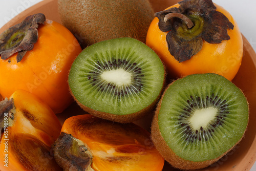 Clay trough with persimmons and kiwis photo