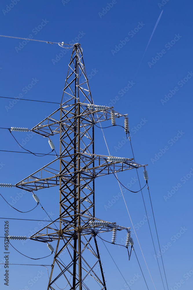 Frost-covered power line pylon on a clear frosty day against a blue sky Frost-covered power line pylon on a clear frosty day against a blue sky