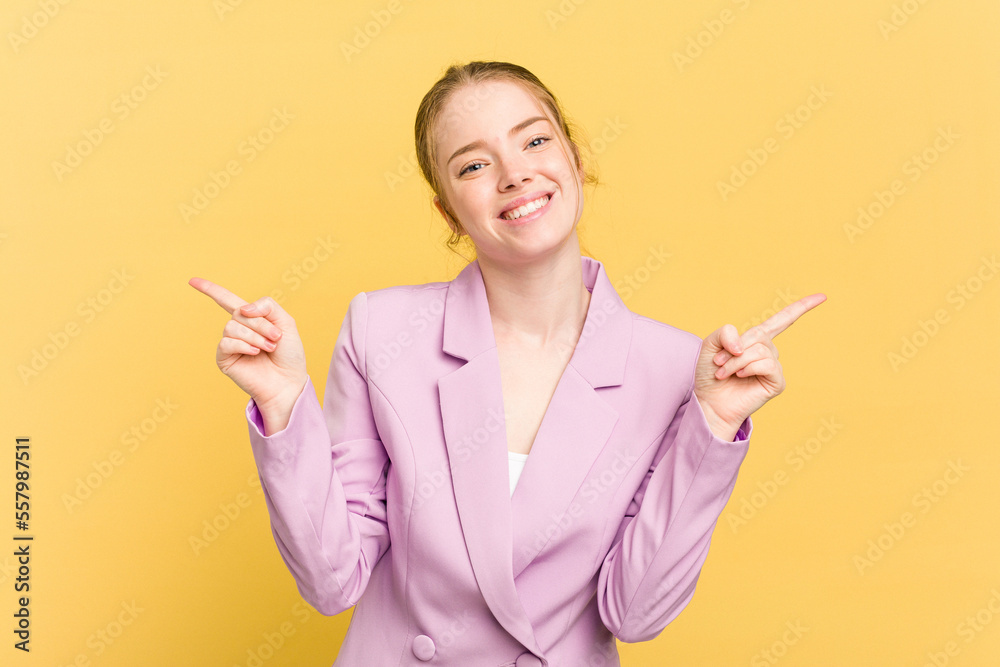 Young caucasian redhead woman isolated on yellow background pointing to different copy spaces, choosing one of them, showing with finger. Young caucasian redhead woman isolated on yellow background pointing to different copy spaces, choosing one of them, showing with finger.