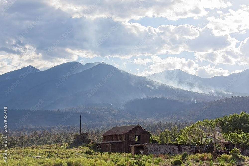 Smoke rising in the mountains in the Schultz Fire near Flagstaff, Arizona. An old structure is in the foreground.