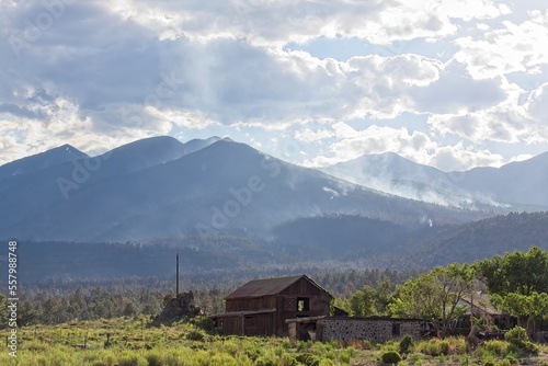 Smoke rising in the mountains in the Schultz Fire near Flagstaff, Arizona. An old structure is in the foreground. photo